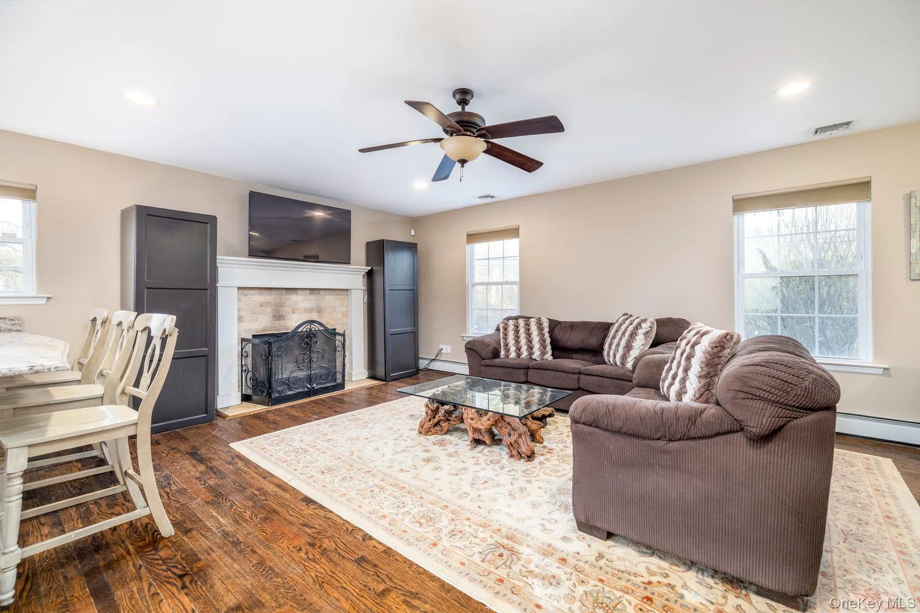 Living area featuring dark wood-type flooring, healthy amount of natural light, a fireplace with raised hearth, and recessed lighting Living area featuring dark wood-type flooring, healthy amount of natural light, a fireplace with raised hearth, and recessed lighting