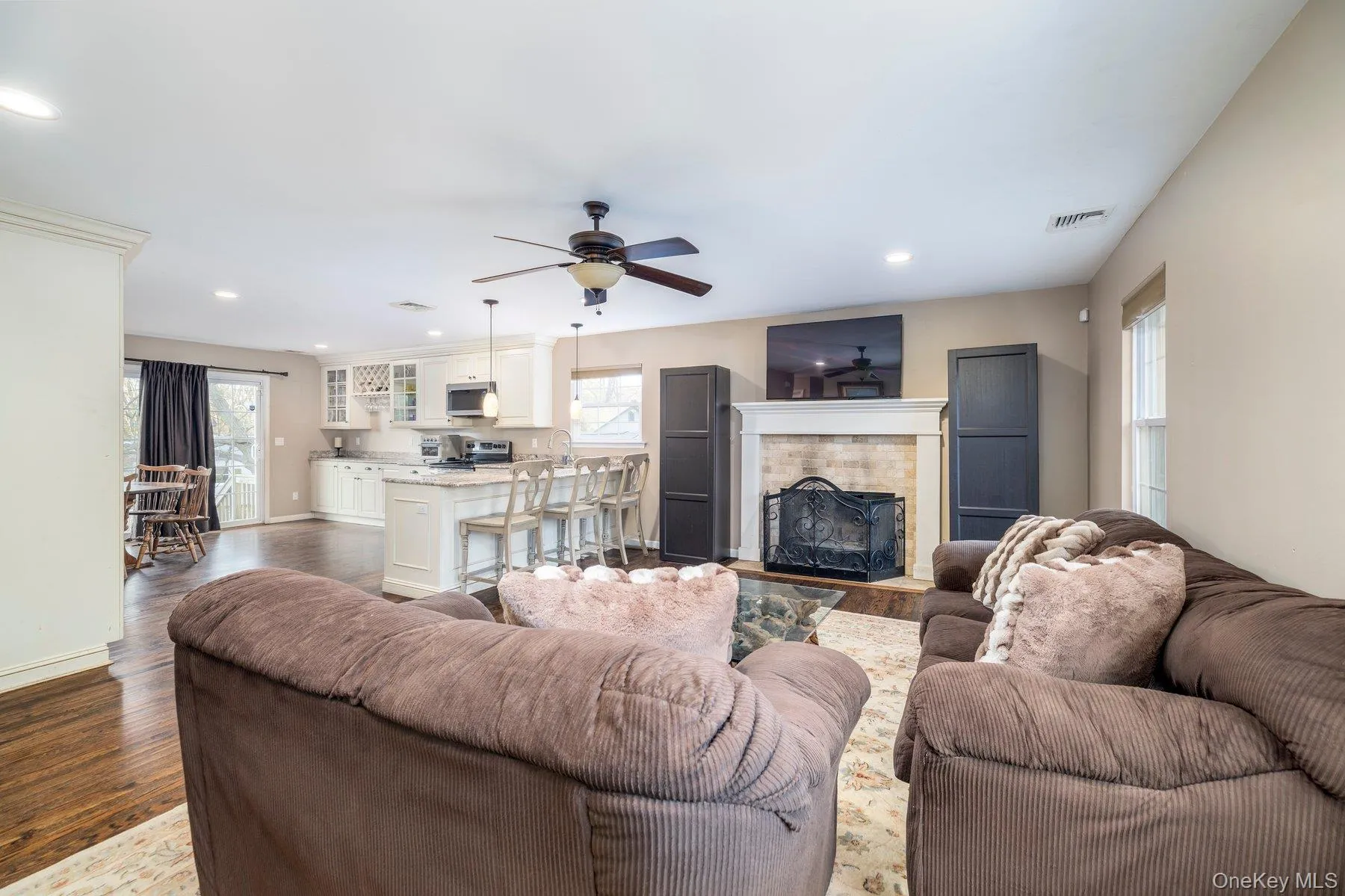 Living room with a fireplace, dark wood-style floors, recessed lighting, and a ceiling fan Living room with a fireplace, dark wood-style floors, recessed lighting, and a ceiling fan