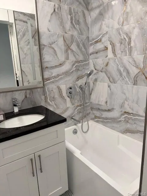 Bathroom with tile walls, vanity, and soaking tub / shower combination Bathroom with tile walls, vanity, and soaking tub / shower combination