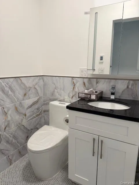 Bathroom with vanity, tile walls, tile patterned floors, and a wainscoted tiled wall Bathroom with vanity, tile walls, tile patterned floors, and a wainscoted tiled wall