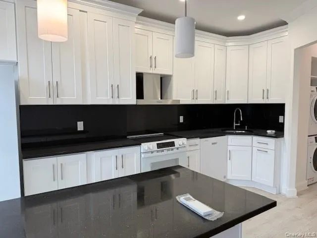 Kitchen with white cabinets, decorative light fixtures, white range with electric stovetop, extractor fan, and light wood finished floors Kitchen with white cabinets, decorative light fixtures, white range with electric stovetop, extractor fan, and light wood finished floors