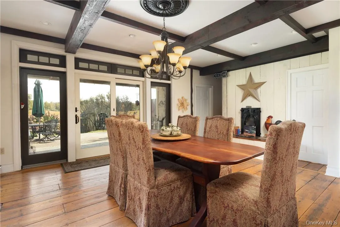 Dining space with beamed ceiling, light hardwood / wood-style flooring, and coffered ceiling and a propane fire;place Dining space with beamed ceiling, light hardwood / wood-style flooring, and coffered ceiling and a propane fire;place