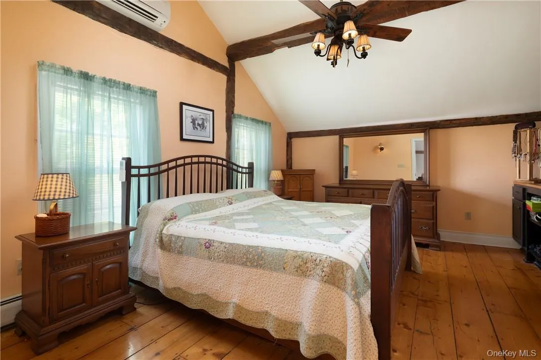 Bedroom with vaulted ceilings and beams, ceiling fan, lofted ceiling, light hardwood , and a wall mounted AC Bedroom with vaulted ceilings and beams, ceiling fan, lofted ceiling, light hardwood , and a wall mounted AC