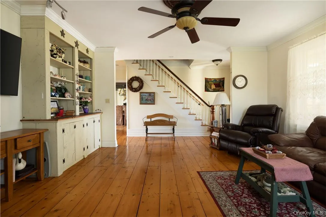 Living room featuring hardwood flooring, crown molding, and ceiling fan Living room featuring hardwood flooring, crown molding, and ceiling fan
