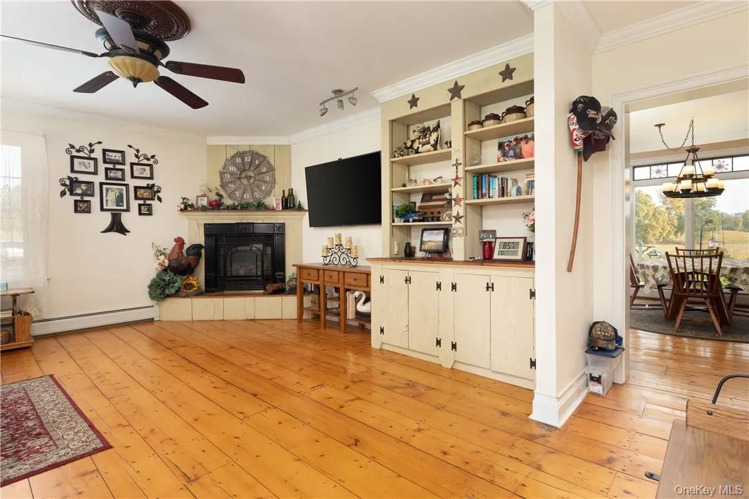 Living room with light hardwood, built ins, ornamental molding, and a propane fireplace Living room with light hardwood, built ins, ornamental molding, and a propane fireplace
