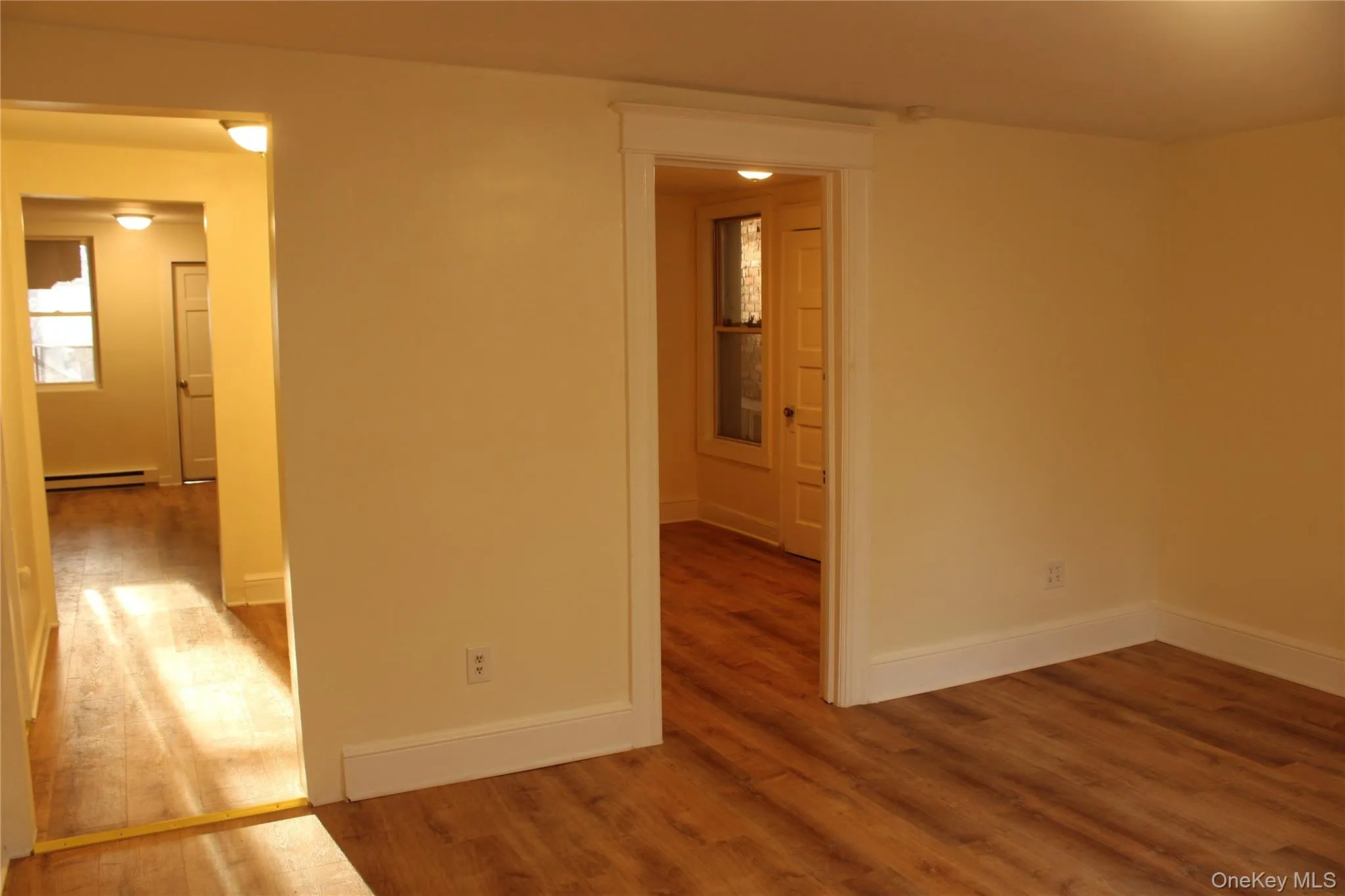 Empty room featuring wood finished floors and baseboard heating Empty room featuring wood finished floors and baseboard heating