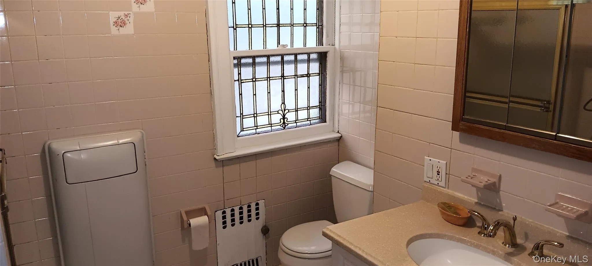 Full bath featuring vanity, radiator, tile walls, and backsplash Full bath featuring vanity, radiator, tile walls, and backsplash
