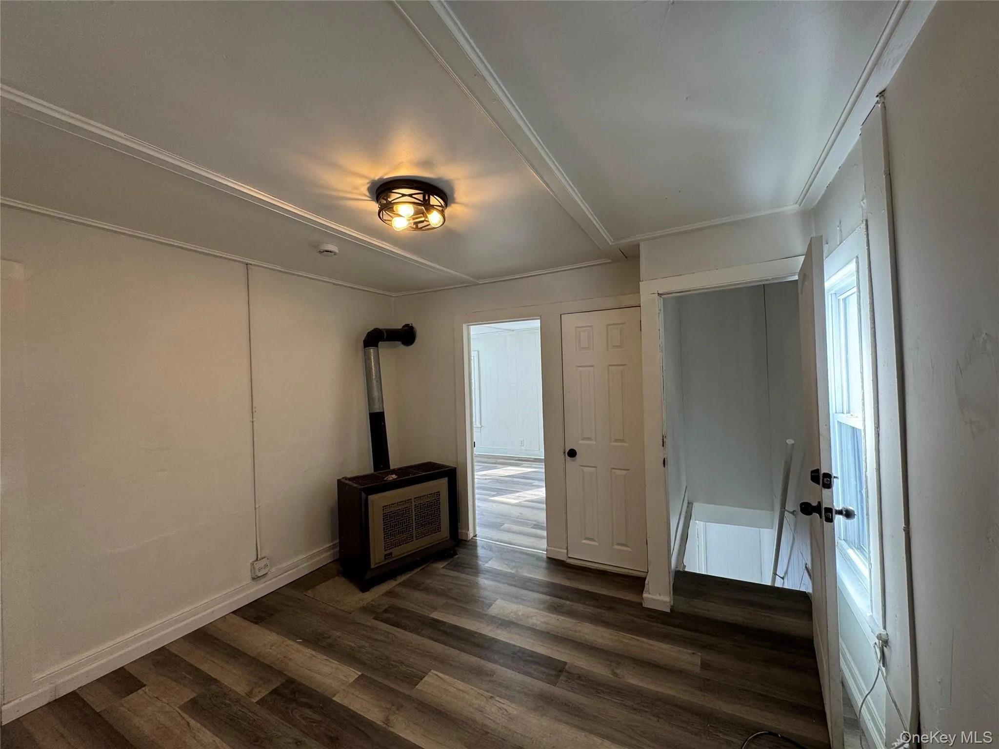 Unfurnished living room featuring dark wood-style floors and baseboards Unfurnished living room featuring dark wood-style floors and baseboards