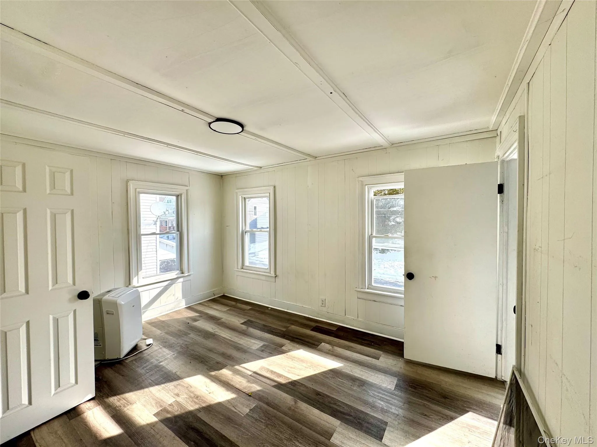 Unfurnished room featuring wooden walls and dark wood-style floors Unfurnished room featuring wooden walls and dark wood-style floors