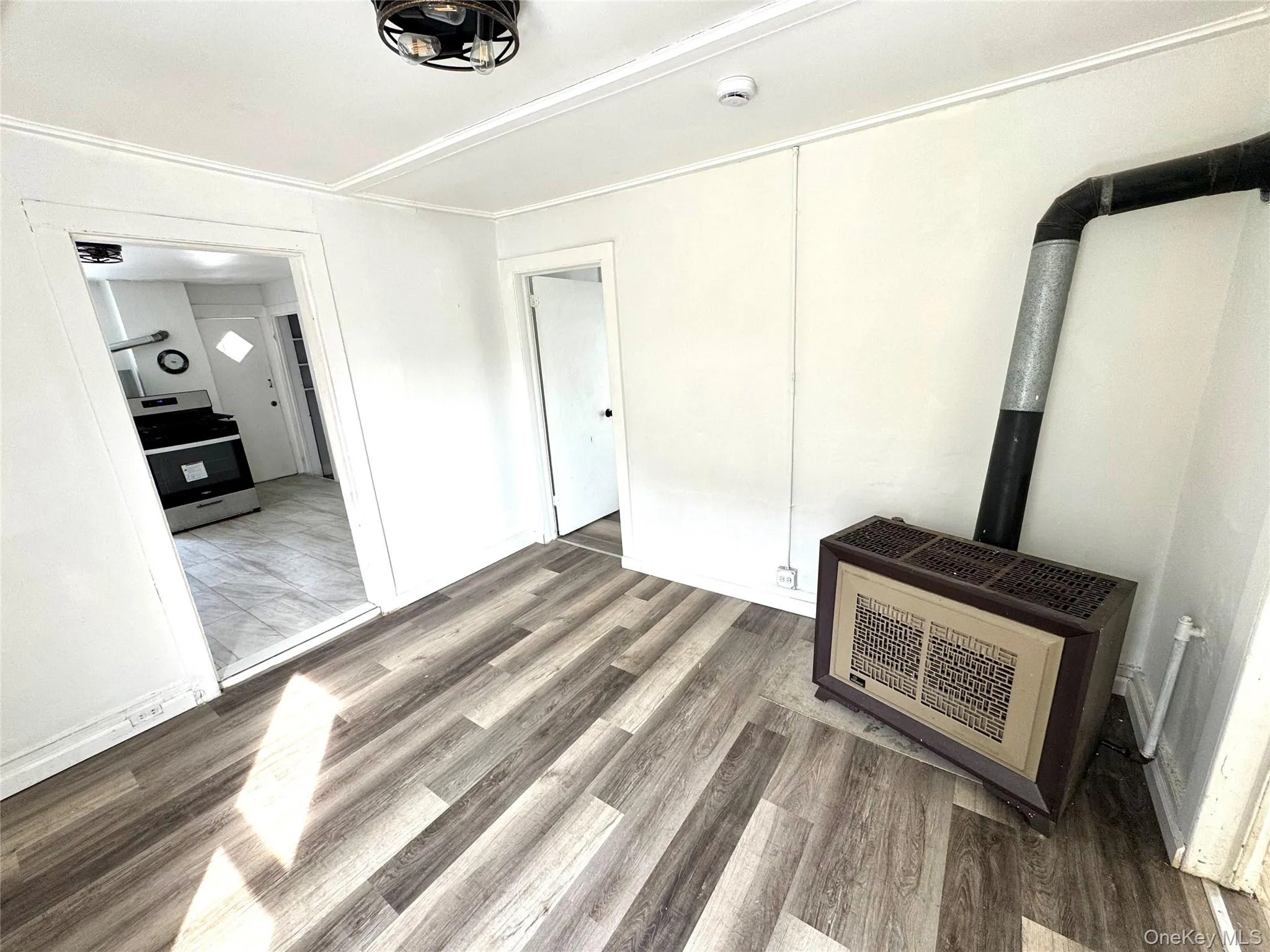 Unfurnished living room featuring wood finished floors, a wood stove, and heating unit Unfurnished living room featuring wood finished floors, a wood stove, and heating unit