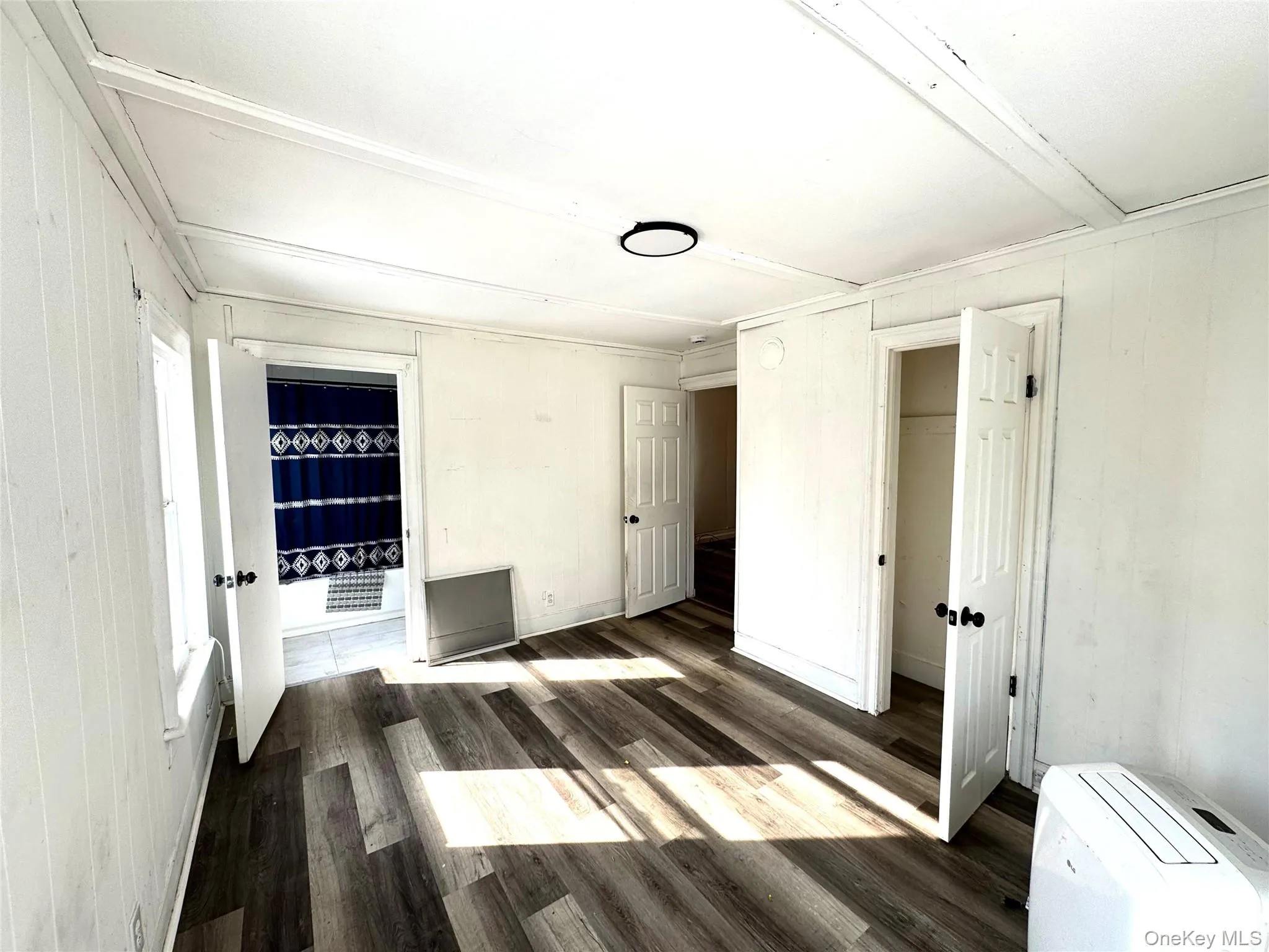 Unfurnished bedroom with wood walls, dark wood-style flooring, and a closet Unfurnished bedroom with wood walls, dark wood-style flooring, and a closet