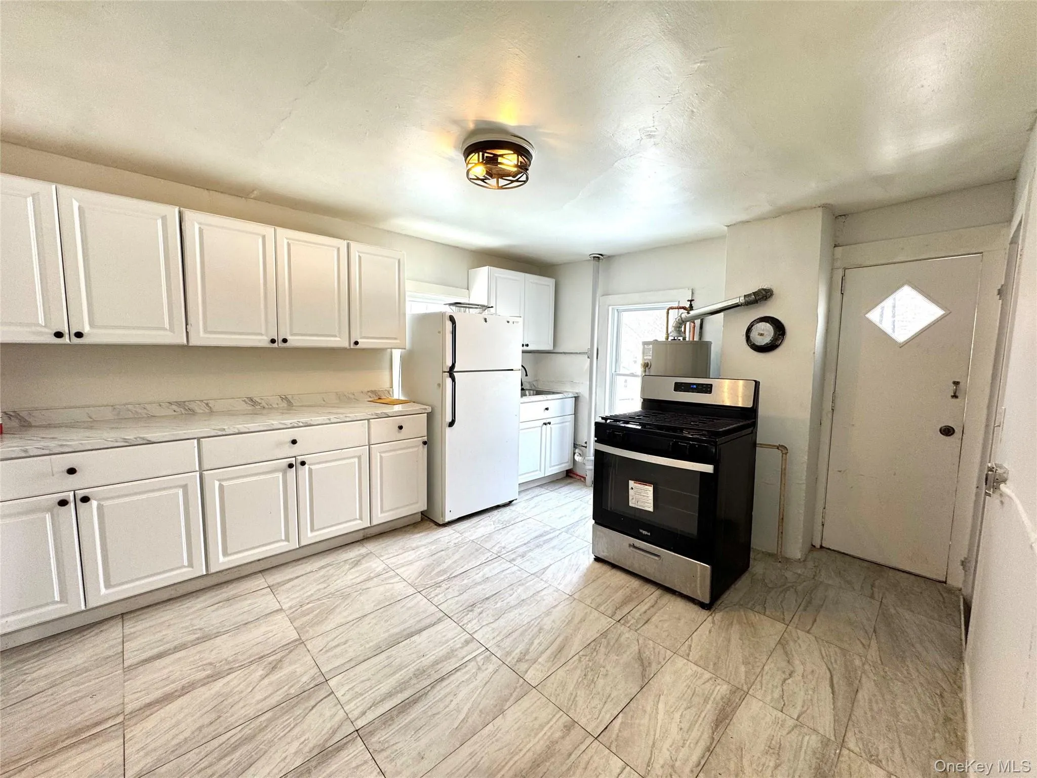 Kitchen with white cabinets, stainless steel range with gas stovetop, light countertops, and freestanding refrigerator Kitchen with white cabinets, stainless steel range with gas stovetop, light countertops, and freestanding refrigerator