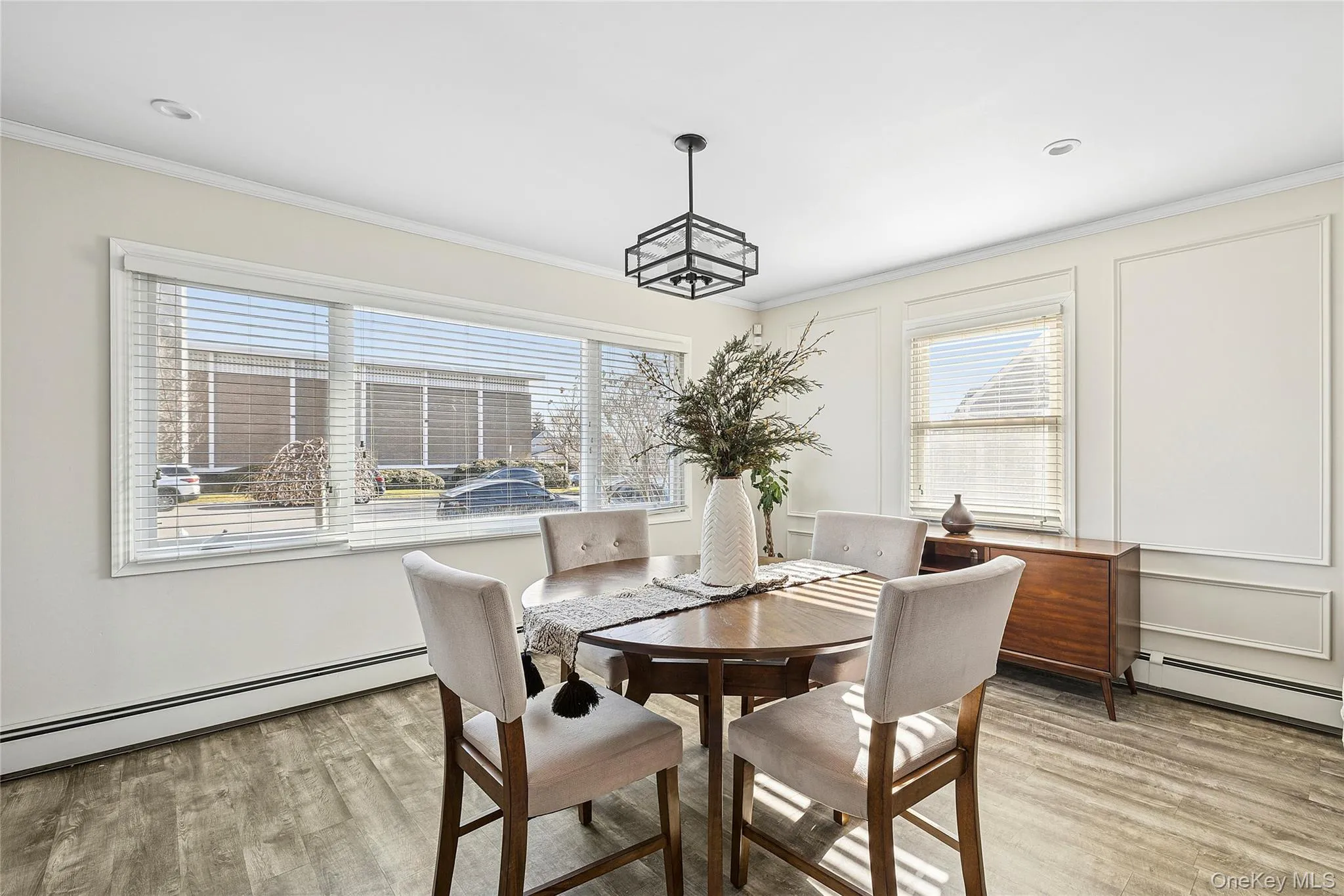 Dining area featuring baseboard heating, plenty of natural light, ornamental molding, and light wood-style floors Dining area featuring baseboard heating, plenty of natural light, ornamental molding, and light wood-style floors