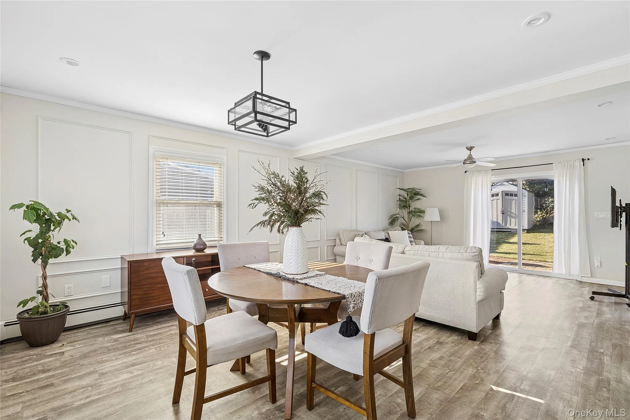 Dining area with a decorative wall, crown molding, light wood finished floors, a baseboard heating unit, and ceiling fan Dining area with a decorative wall, crown molding, light wood finished floors, a baseboard heating unit, and ceiling fan