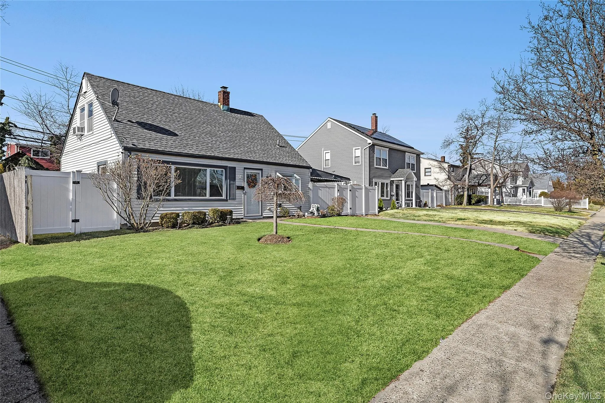 Rear view of house with roof with shingles, a chimney, a gate, and a residential view Rear view of house with roof with shingles, a chimney, a gate, and a residential view
