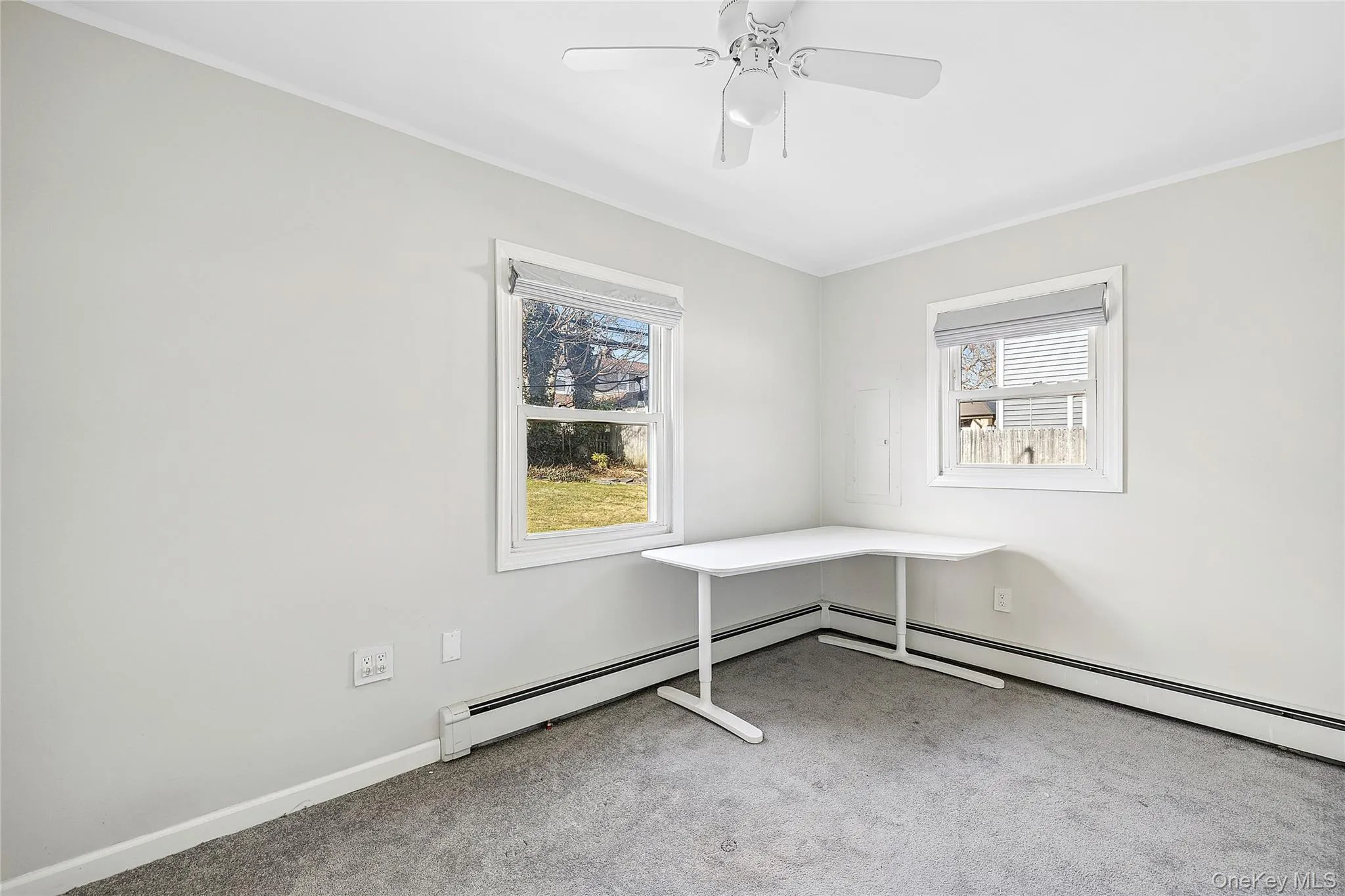 Unfurnished room with healthy amount of natural light, light colored carpet, baseboard heating, crown molding, and ceiling fan Unfurnished room with healthy amount of natural light, light colored carpet, baseboard heating, crown molding, and ceiling fan
