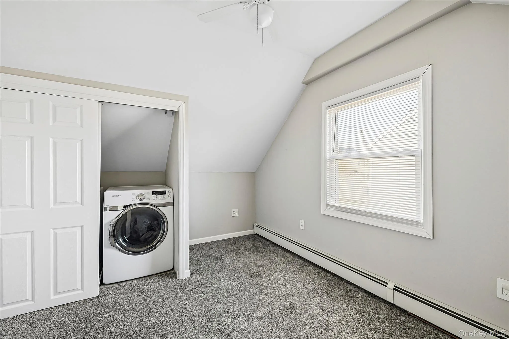 Laundry area featuring a baseboard heating unit, washer / clothes dryer, vaulted ceiling, carpet flooring, and ceiling fan Laundry area featuring a baseboard heating unit, washer / clothes dryer, vaulted ceiling, carpet flooring, and ceiling fan