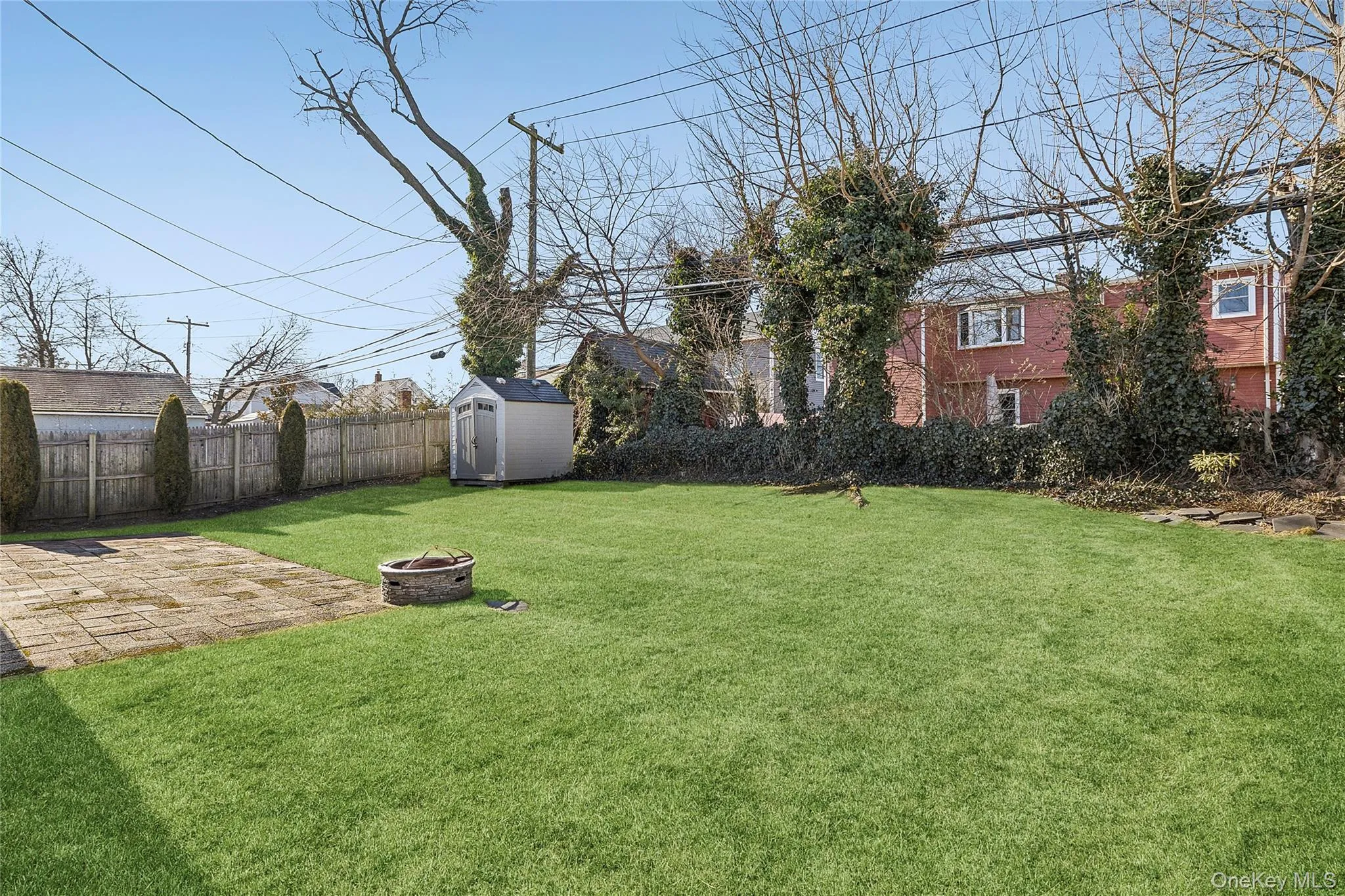Fenced backyard featuring an outdoor fire pit, a storage shed, and a patio area Fenced backyard featuring an outdoor fire pit, a storage shed, and a patio area