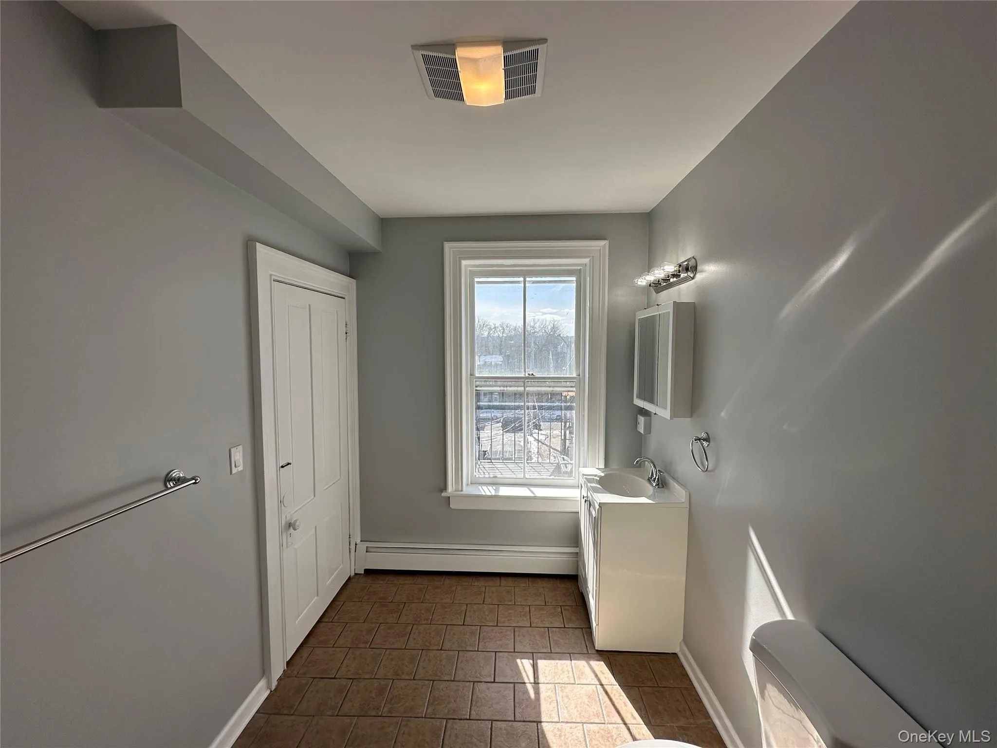 Bathroom featuring tile patterned floors, sink, and a baseboard radiator Bathroom featuring tile patterned floors, sink, and a baseboard radiator