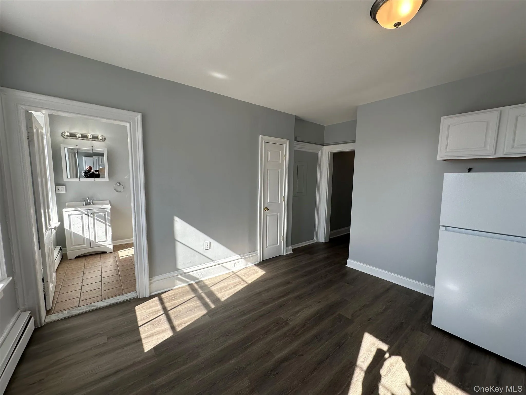 Unfurnished dining area with sink, dark wood-type flooring, and a baseboard radiator Unfurnished dining area with sink, dark wood-type flooring, and a baseboard radiator