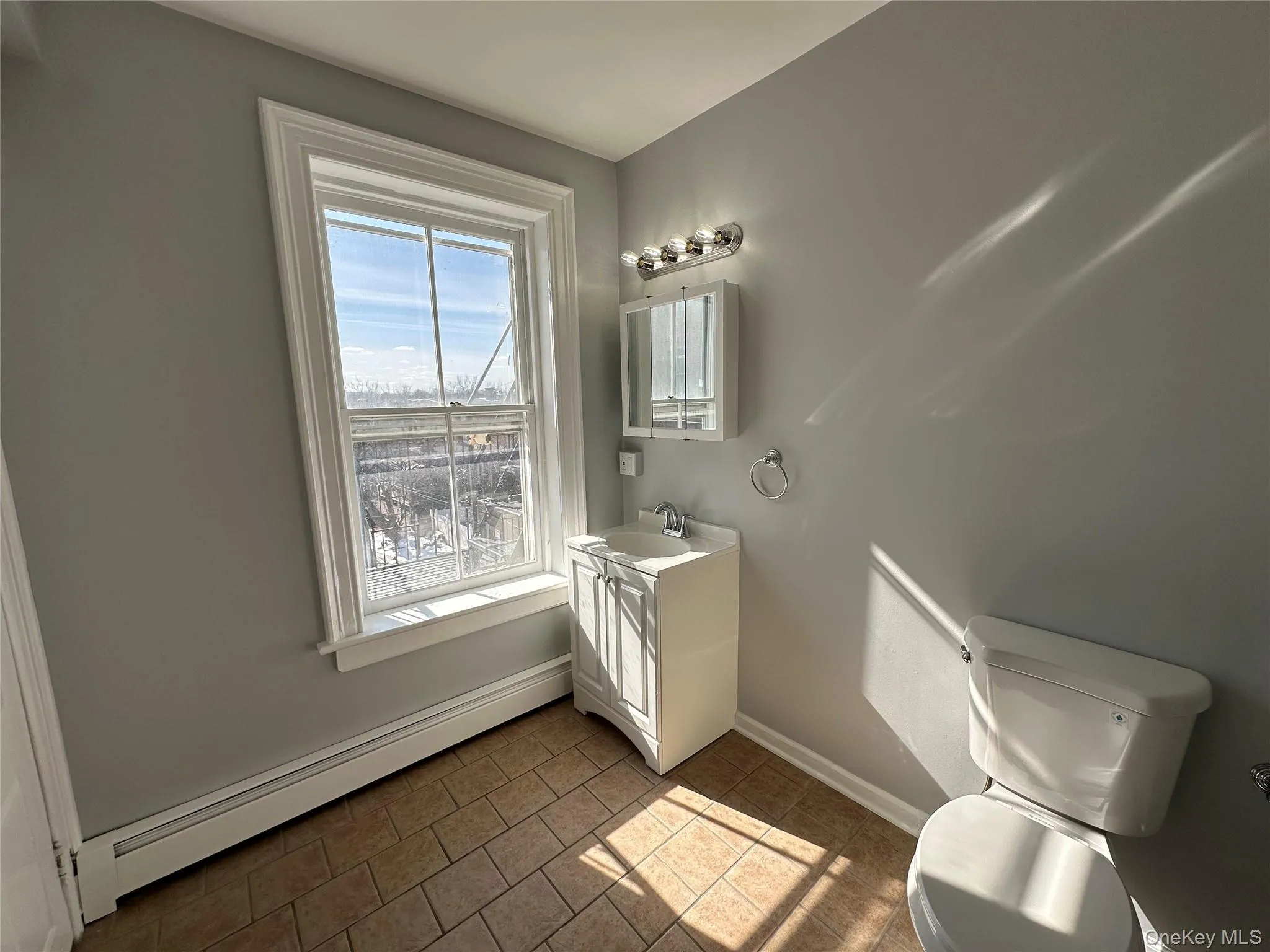 Bathroom with a baseboard heating unit, toilet, vanity, and tile patterned floors Bathroom with a baseboard heating unit, toilet, vanity, and tile patterned floors