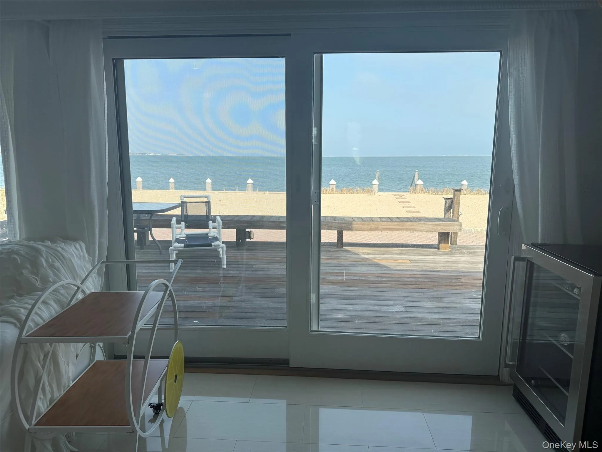 Doorway featuring a water view, wine cooler, and tile patterned flooring Doorway featuring a water view, wine cooler, and tile patterned flooring