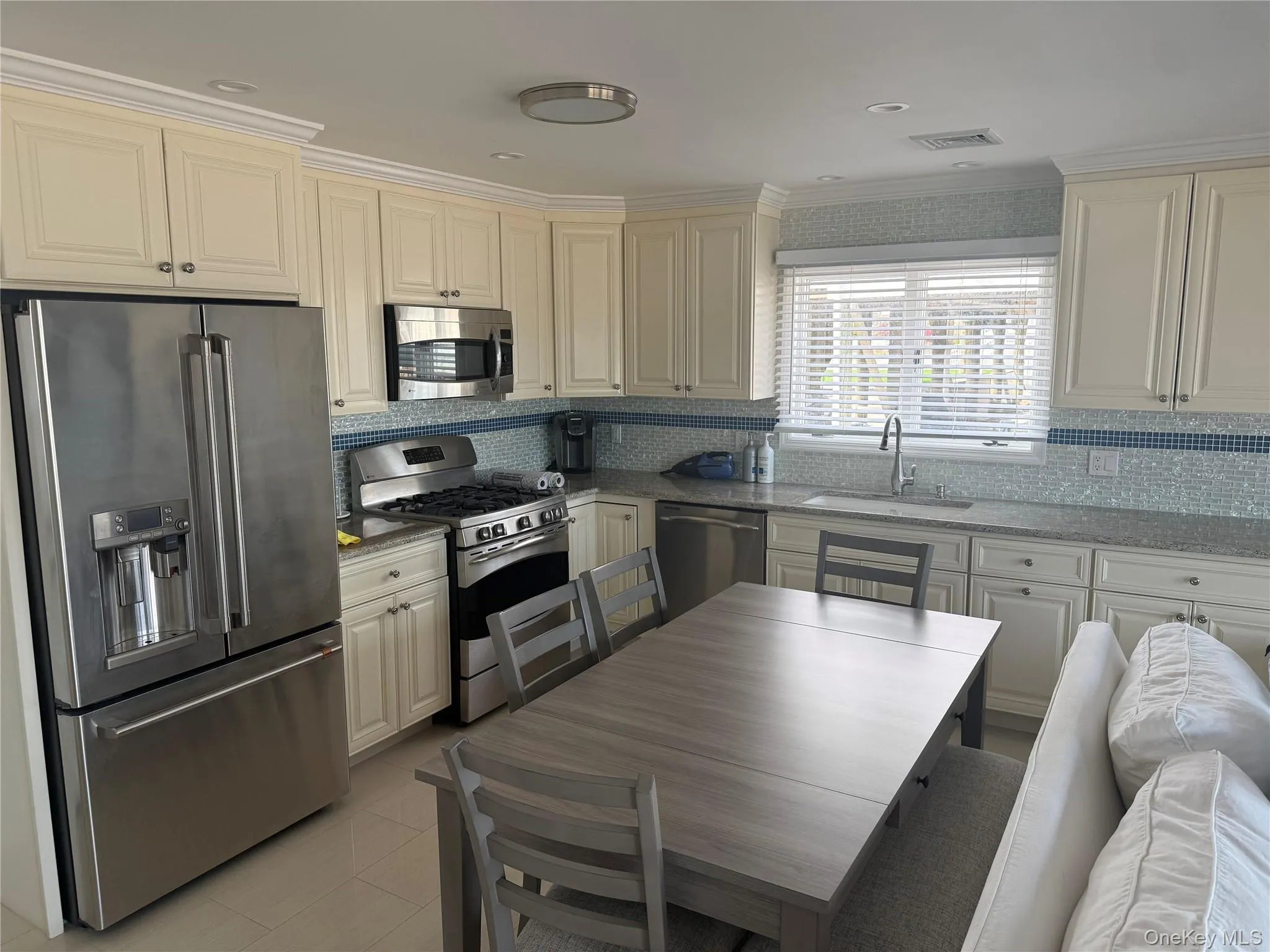 Kitchen with a sink, backsplash, visible vents, and appliances with stainless steel finishes Kitchen with a sink, backsplash, visible vents, and appliances with stainless steel finishes