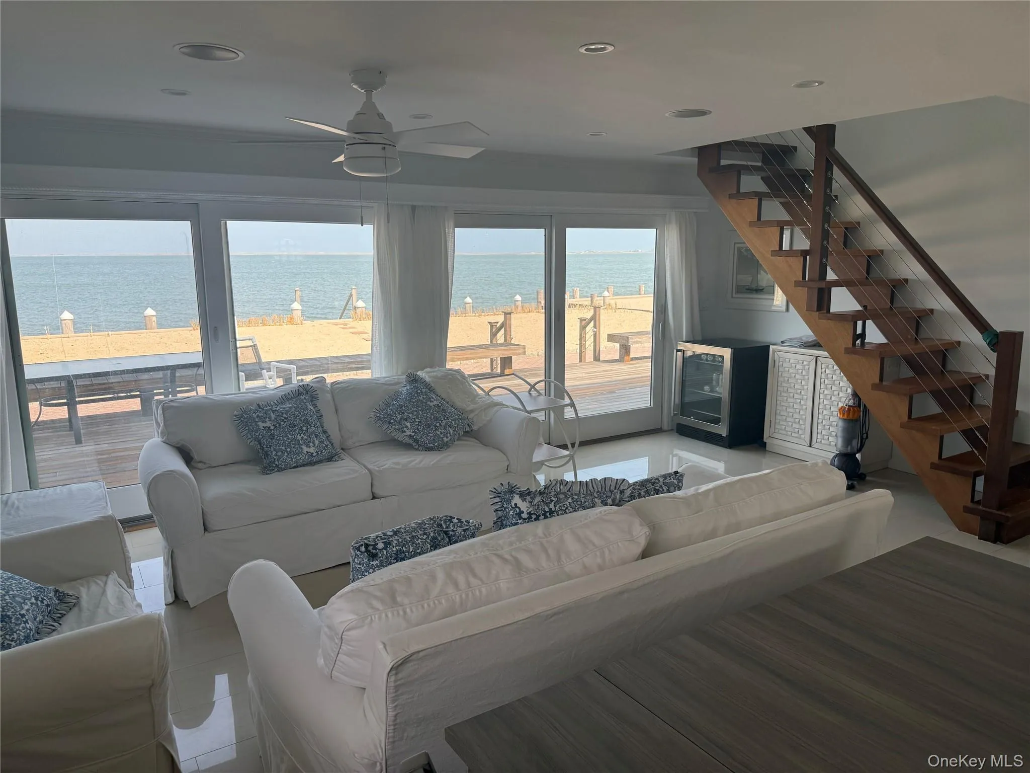 Living area featuring a water view, stairs, ceiling fan, and light tile patterned flooring Living area featuring a water view, stairs, ceiling fan, and light tile patterned flooring