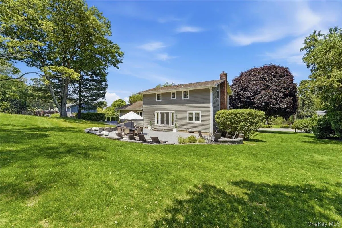 Extensive rear yard with a stone patio, built-in fire pit, and double doors providing exterior access Extensive rear yard with a stone patio, built-in fire pit, and double doors providing exterior access