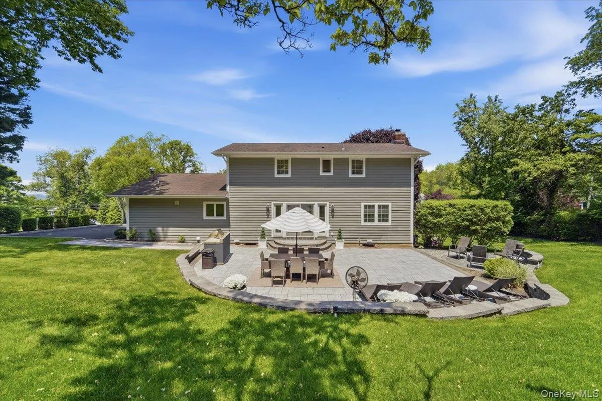 Expansive paver patio with a curved stone retaining wall, offering multiple zones for outdoor living Expansive paver patio with a curved stone retaining wall, offering multiple zones for outdoor living