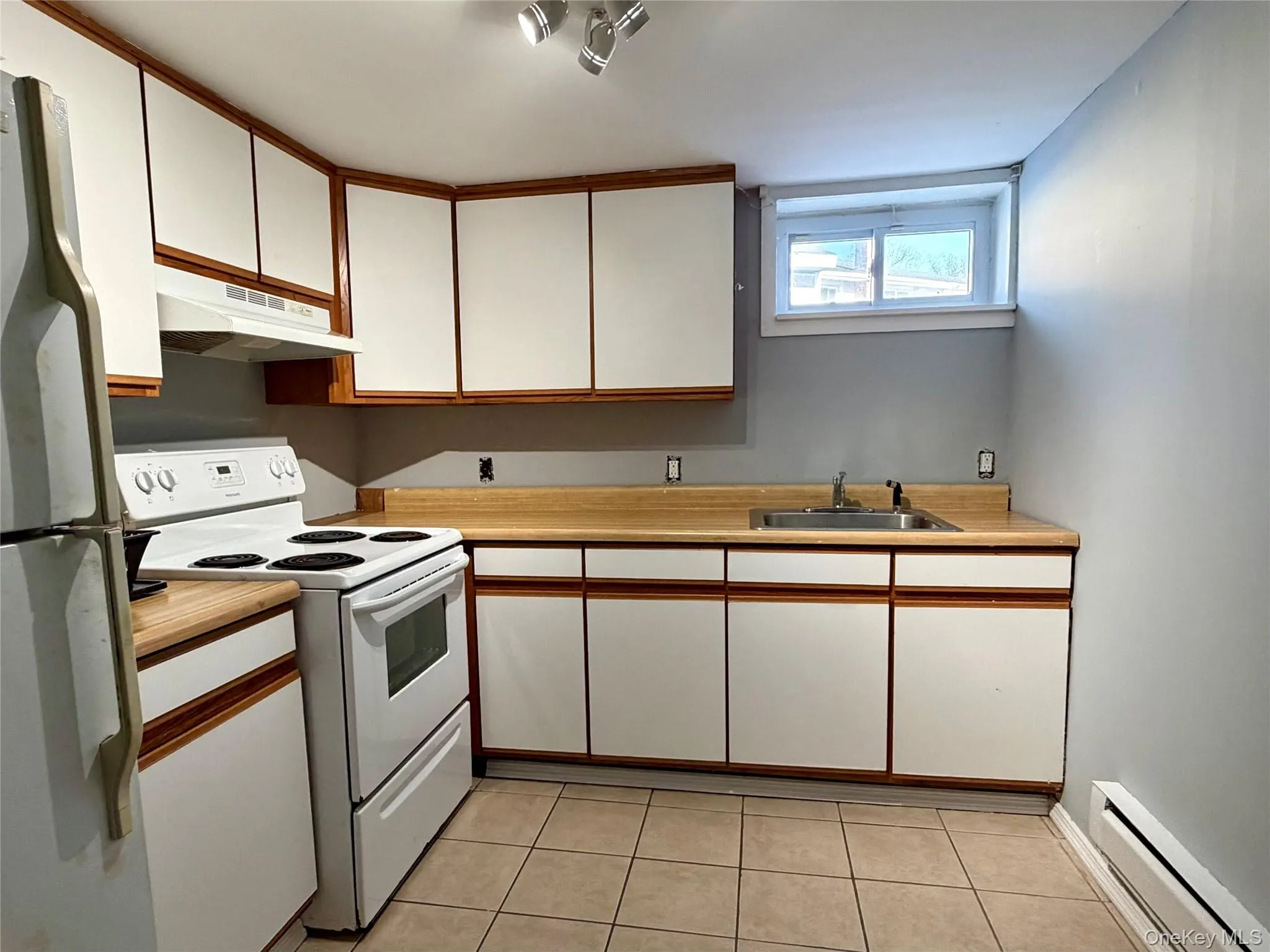 Kitchen featuring white cabinetry, electric range, baseboard heating, light countertops, and freestanding refrigerator Kitchen featuring white cabinetry, electric range, baseboard heating, light countertops, and freestanding refrigerator