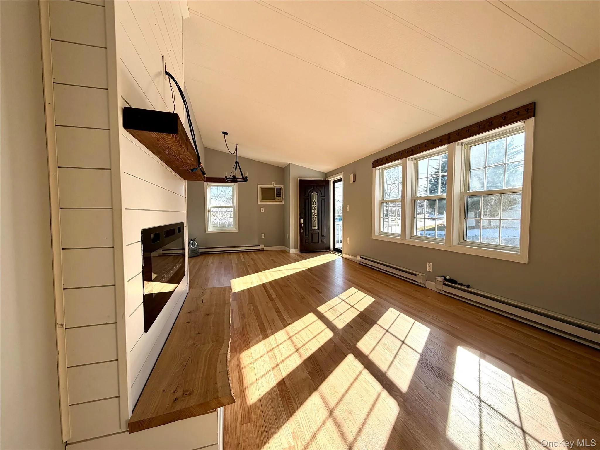 living room featuring light wood finished floors, lofted ceiling, a baseboard heating unit, and a glass covered fireplace!! living room featuring light wood finished floors, lofted ceiling, a baseboard heating unit, and a glass covered fireplace!!