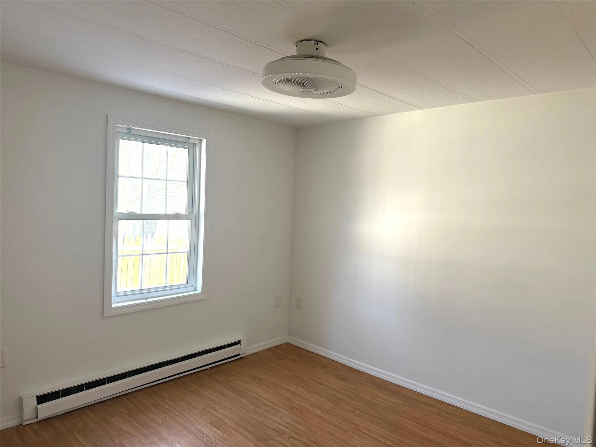 Spare room with a baseboard radiator and light wood-style flooring Spare room with a baseboard radiator and light wood-style flooring