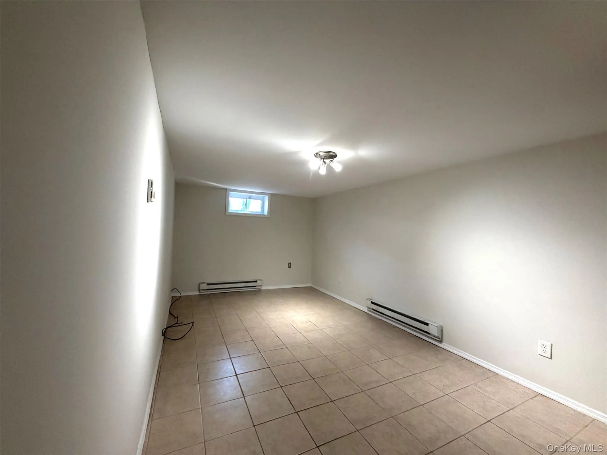 Unfurnished room with a baseboard heating unit and light tile patterned floors Unfurnished room with a baseboard heating unit and light tile patterned floors