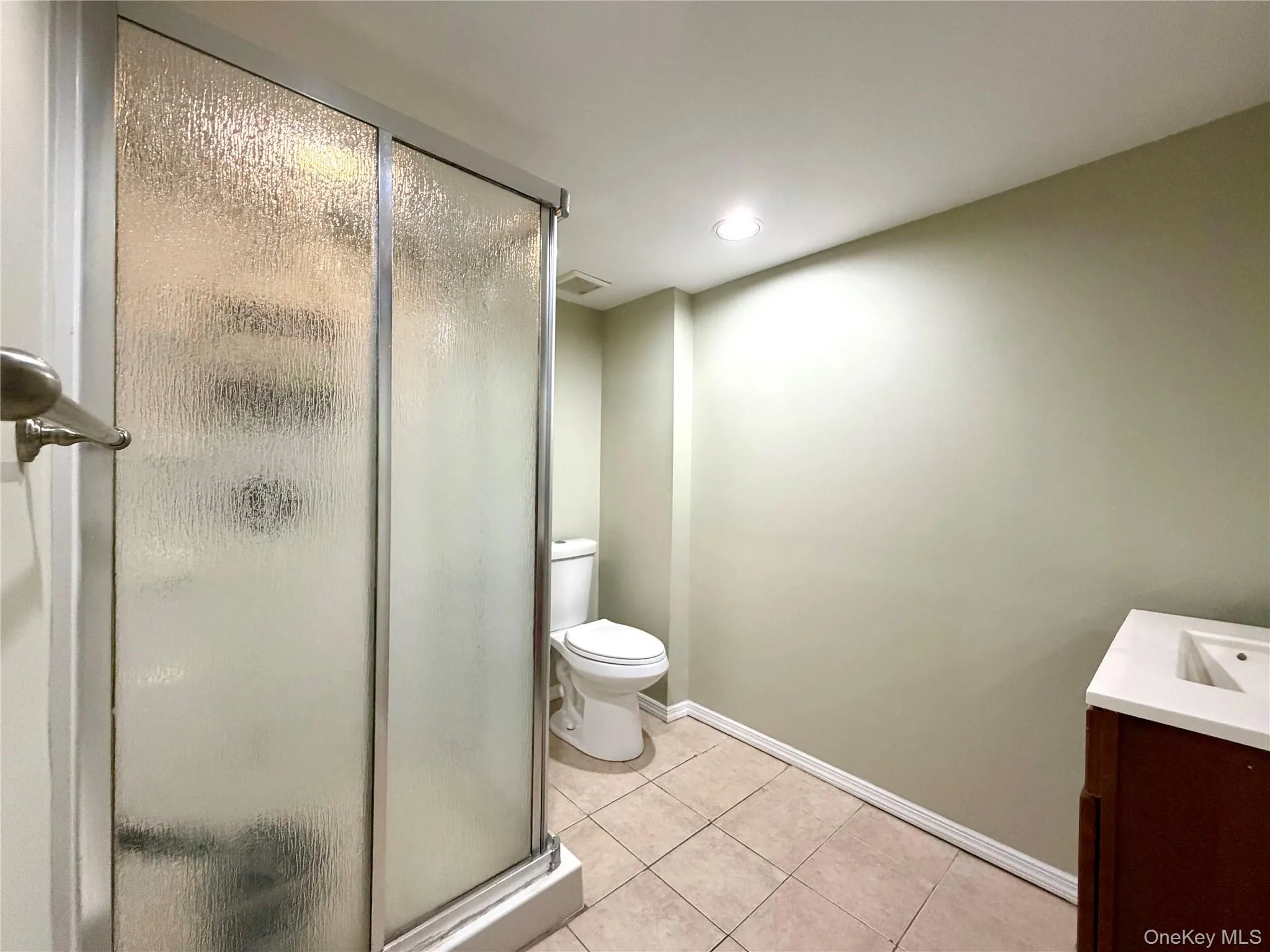 Full bath featuring vanity, a stall shower, light tile patterned flooring, and recessed lighting Full bath featuring vanity, a stall shower, light tile patterned flooring, and recessed lighting