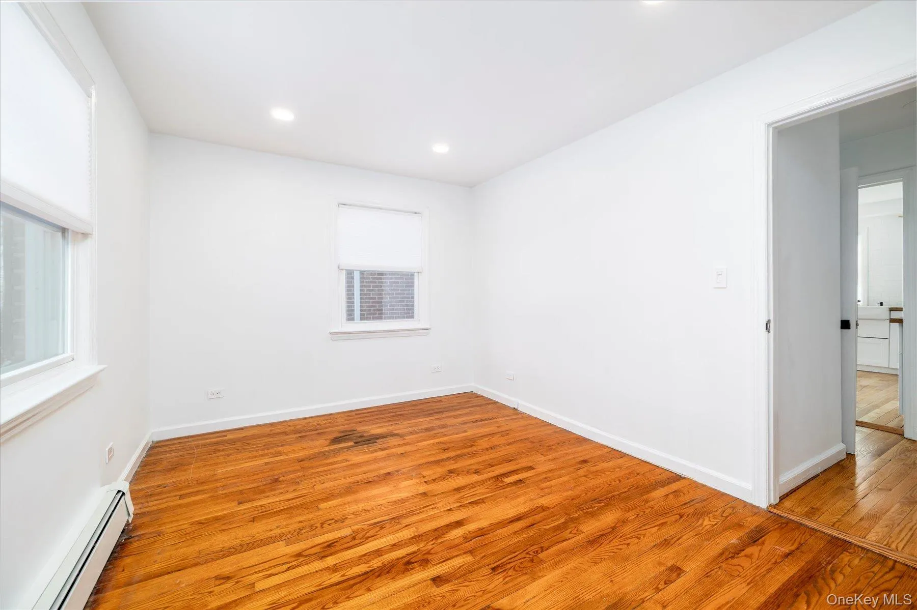 Empty room featuring a baseboard radiator, light wood-type flooring, and recessed lighting Empty room featuring a baseboard radiator, light wood-type flooring, and recessed lighting