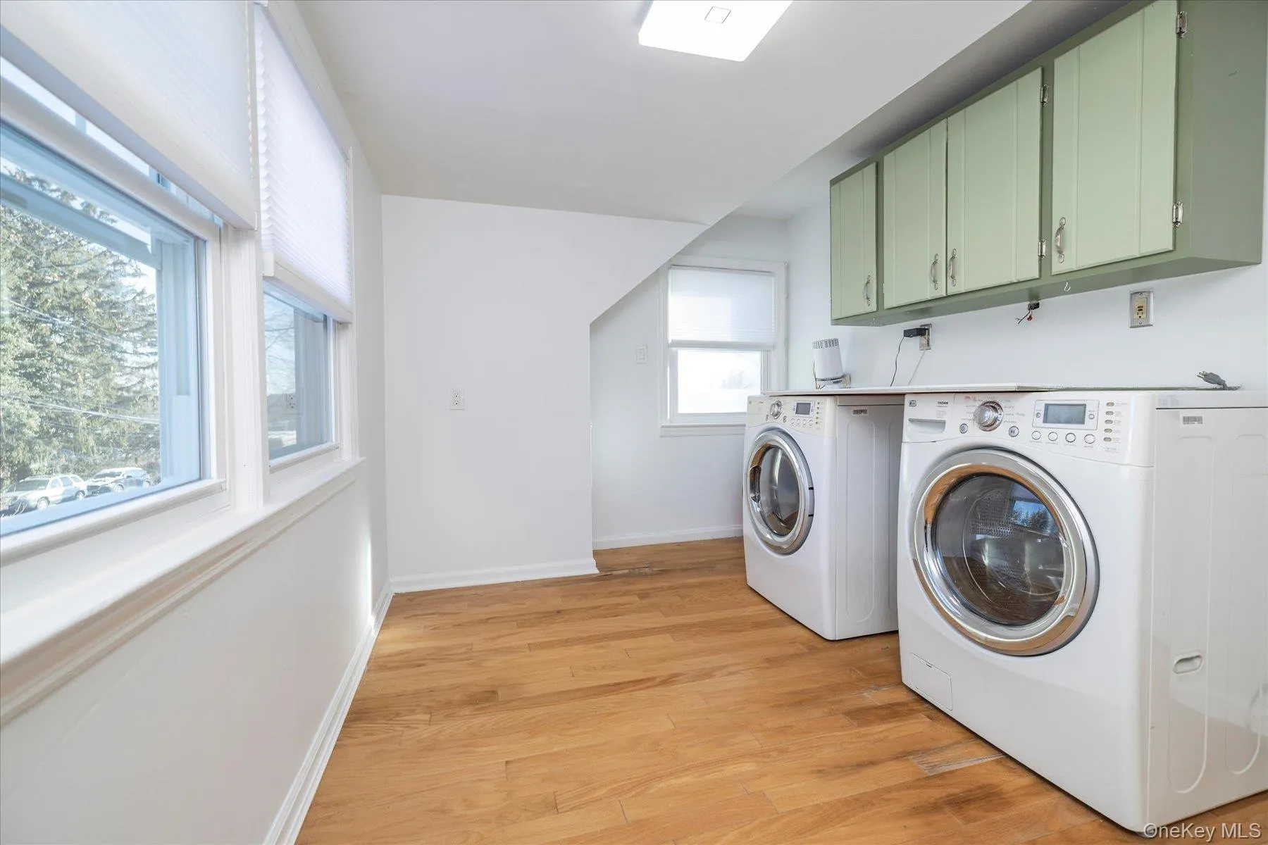 Laundry room featuring light wood finished floors, independent washer and dryer, and cabinet space Laundry room featuring light wood finished floors, independent washer and dryer, and cabinet space