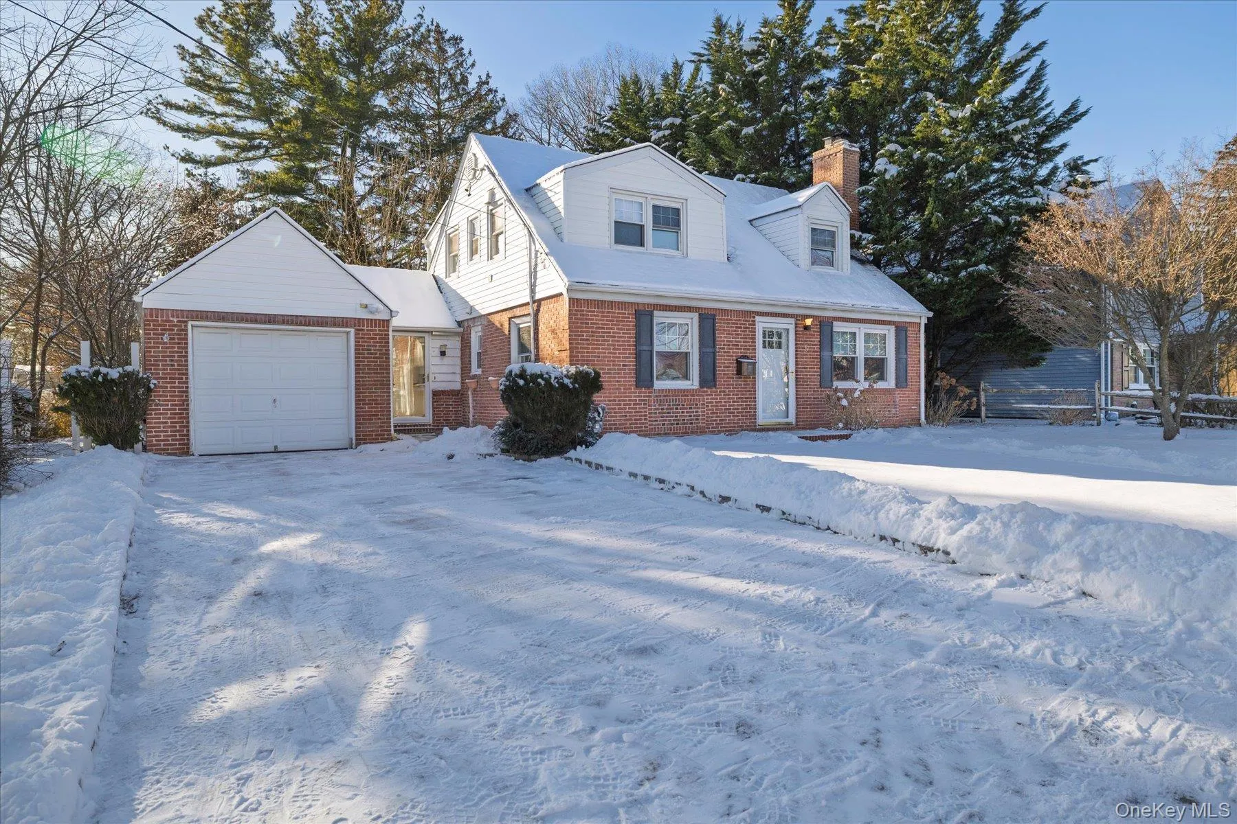 New england style home with a chimney, brick siding, and a garage New england style home with a chimney, brick siding, and a garage