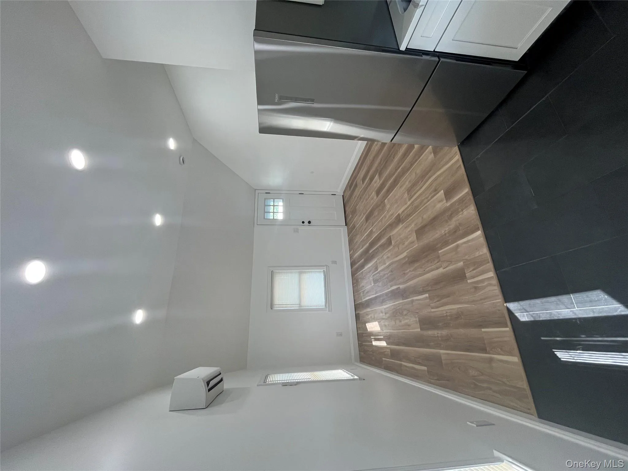 View from Kitchen into living room featuring vaulted ceiling, dark tile patterned flooring, recessed lighting, and a wall mounted AC View from Kitchen into living room featuring vaulted ceiling, dark tile patterned flooring, recessed lighting, and a wall mounted AC