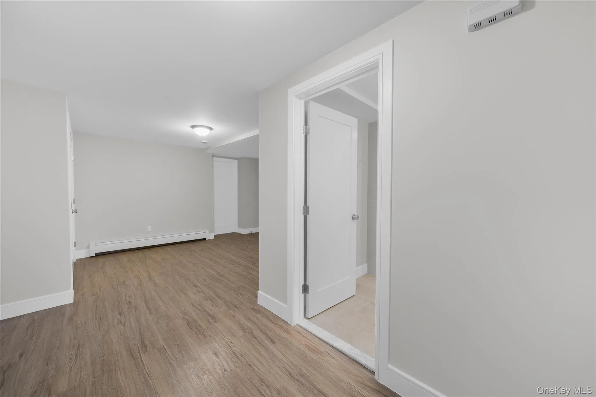 Unfurnished room with a baseboard heating unit and wood finished floors Unfurnished room with a baseboard heating unit and wood finished floors