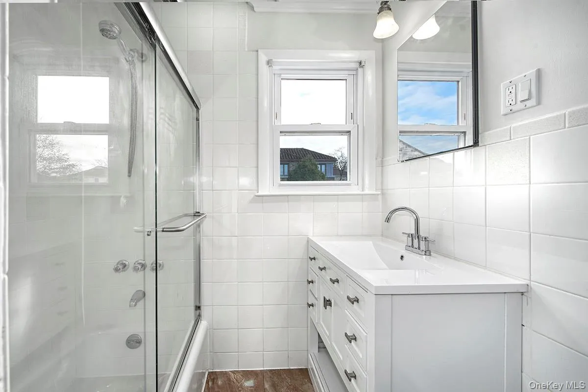 Updated Bathroom featuring vanity, tile walls, and enclosed tub / shower combo Updated Bathroom featuring vanity, tile walls, and enclosed tub / shower combo