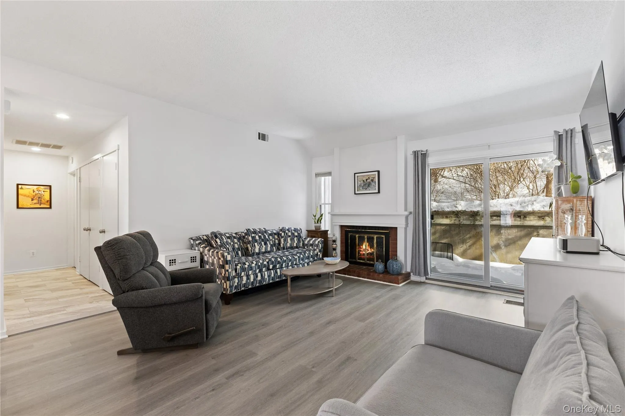 Living room with a wood burning fireplace and a slider to the patio. Brazilian wood-laminate floor. Living room with a wood burning fireplace and a slider to the patio. Brazilian wood-laminate floor.