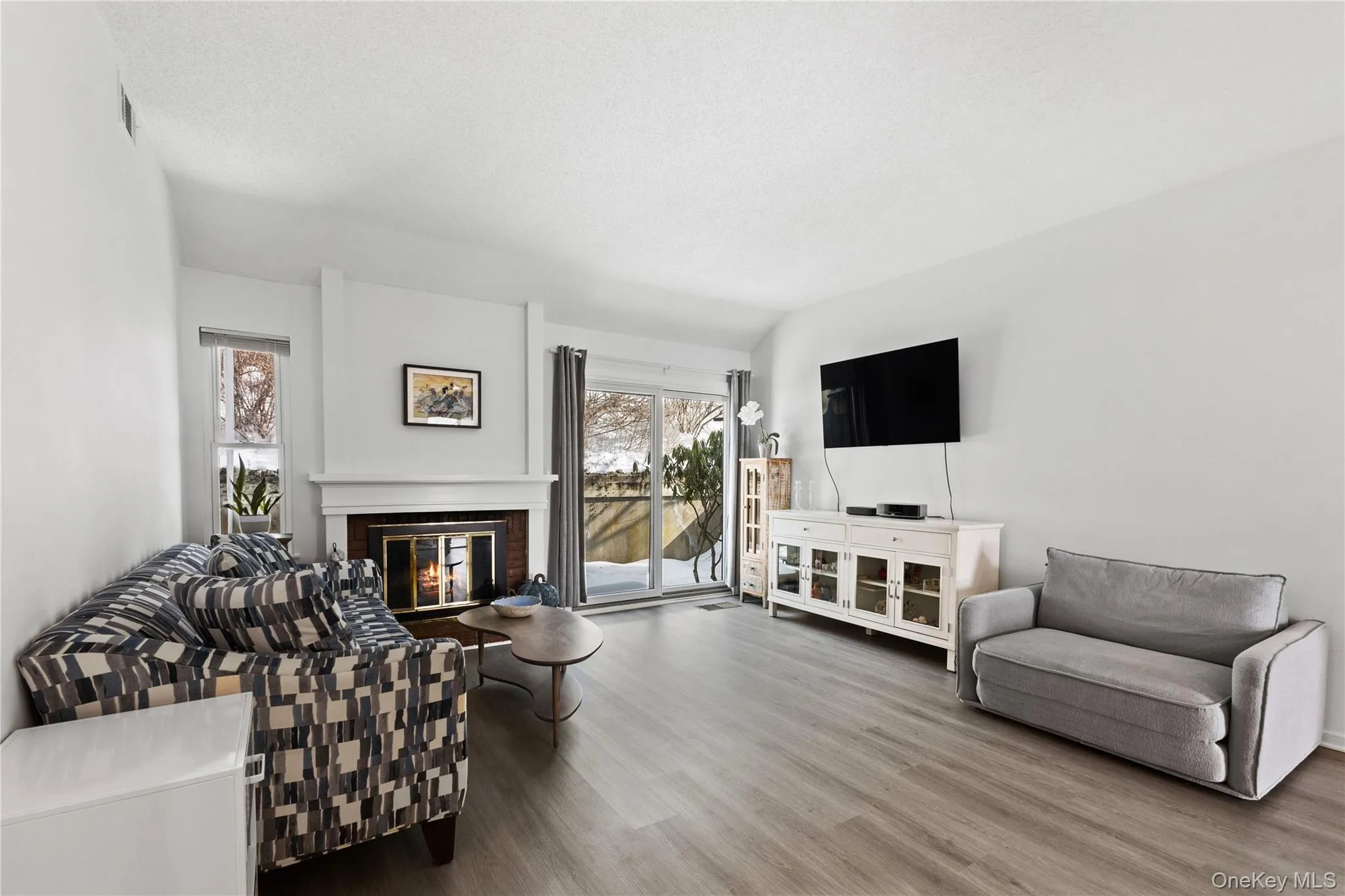 Spacious living room with a wood-burning fireplace and slider to patio. Brazilian wood-laminate floor. Spacious living room with a wood-burning fireplace and slider to patio. Brazilian wood-laminate floor.