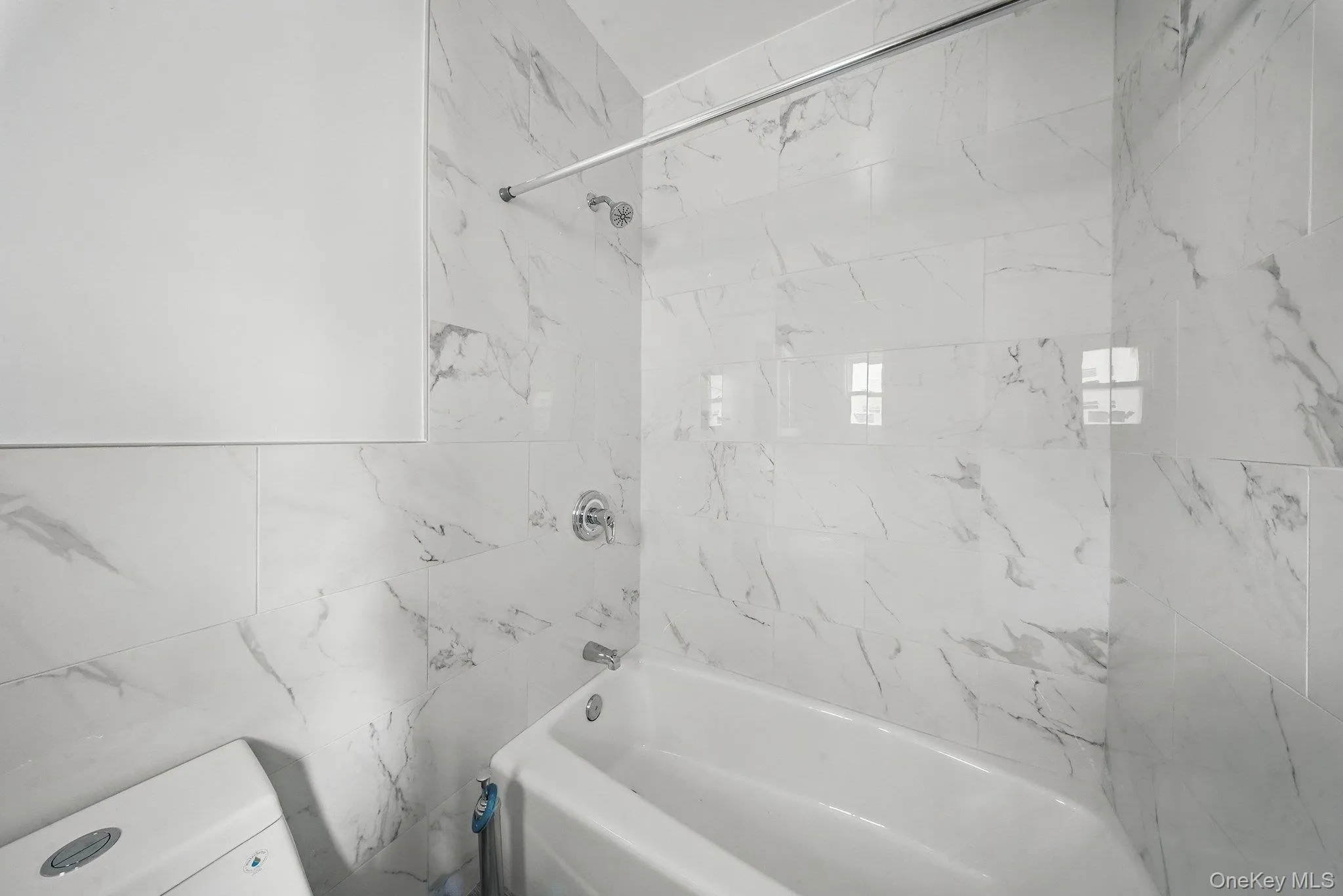 Full bathroom with shower combination, toilet, and tile walls Full bathroom with shower combination, toilet, and tile walls