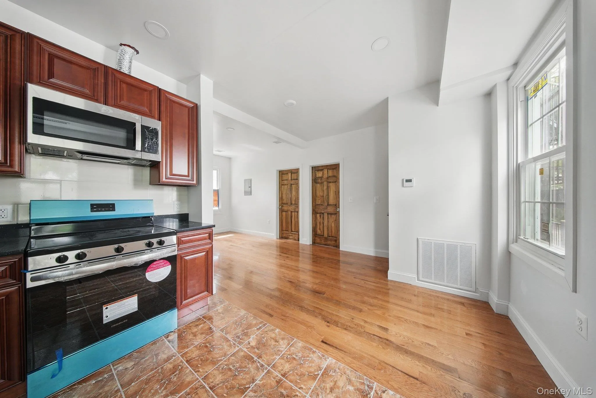 Kitchen with appliances with stainless steel finishes, dark granite countertops, baseboards, and dark brown cabinets Kitchen with appliances with stainless steel finishes, dark granite countertops, baseboards, and dark brown cabinets