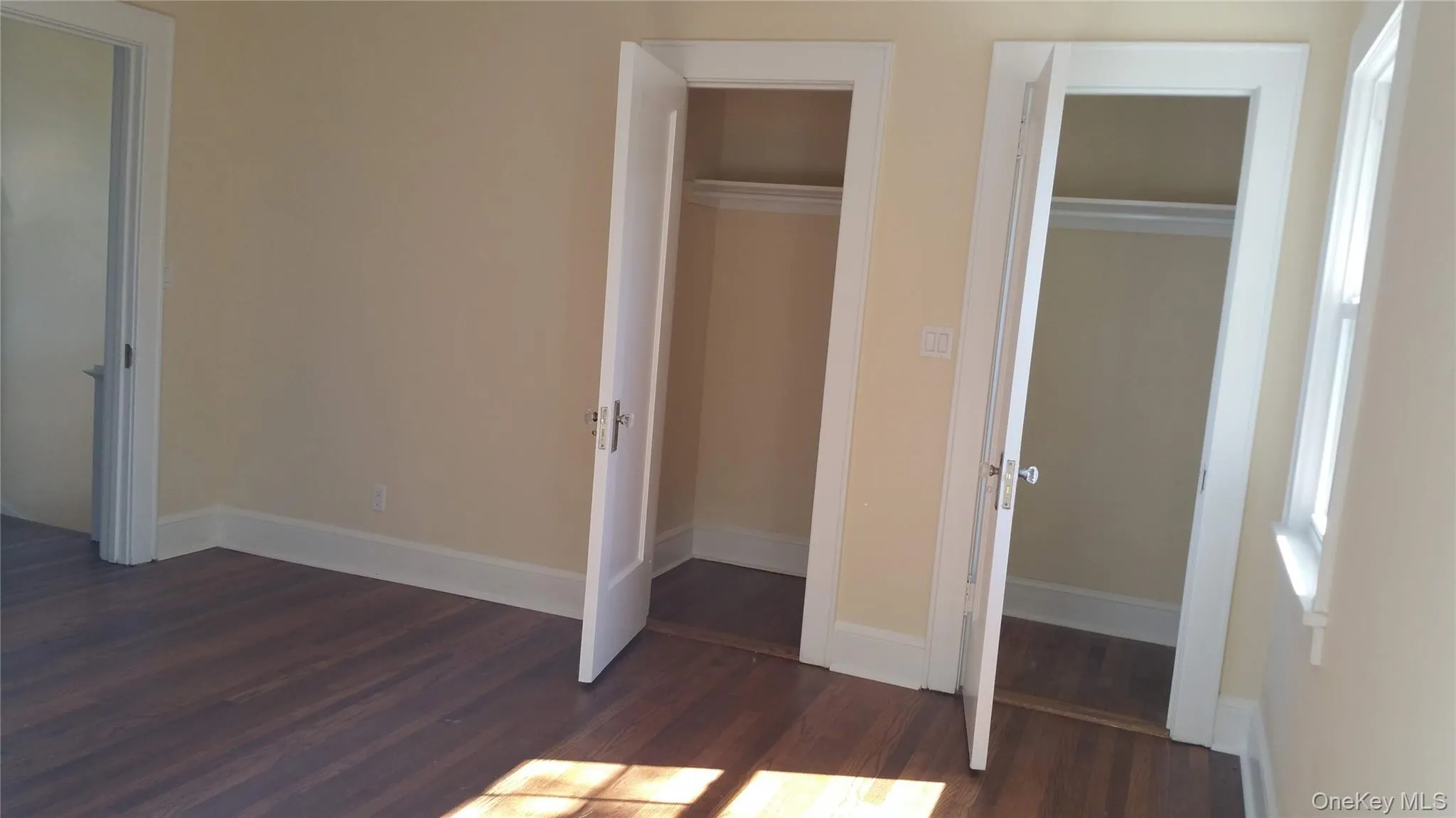 Unfurnished bedroom featuring dark wood-style flooring and baseboards Unfurnished bedroom featuring dark wood-style flooring and baseboards