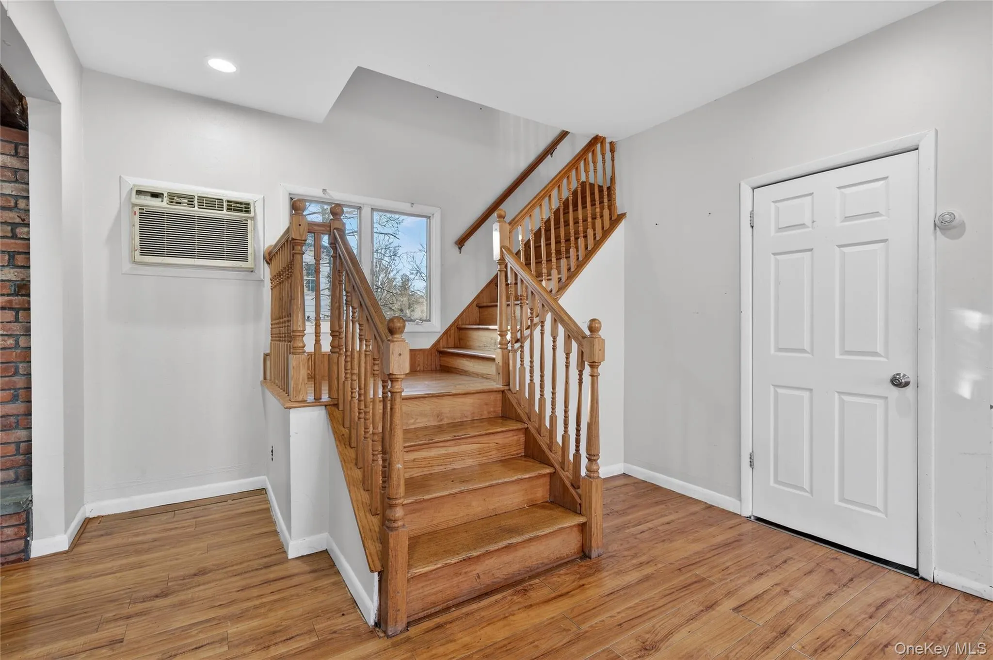 Staircase featuring a wall mounted AC and wood finished floors Staircase featuring a wall mounted AC and wood finished floors