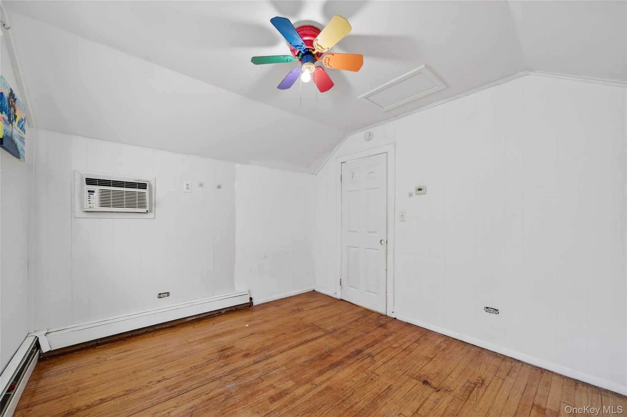Additional living space featuring attic access, lofted ceiling, wood-type flooring, a baseboard radiator, and ceiling fan Additional living space featuring attic access, lofted ceiling, wood-type flooring, a baseboard radiator, and ceiling fan
