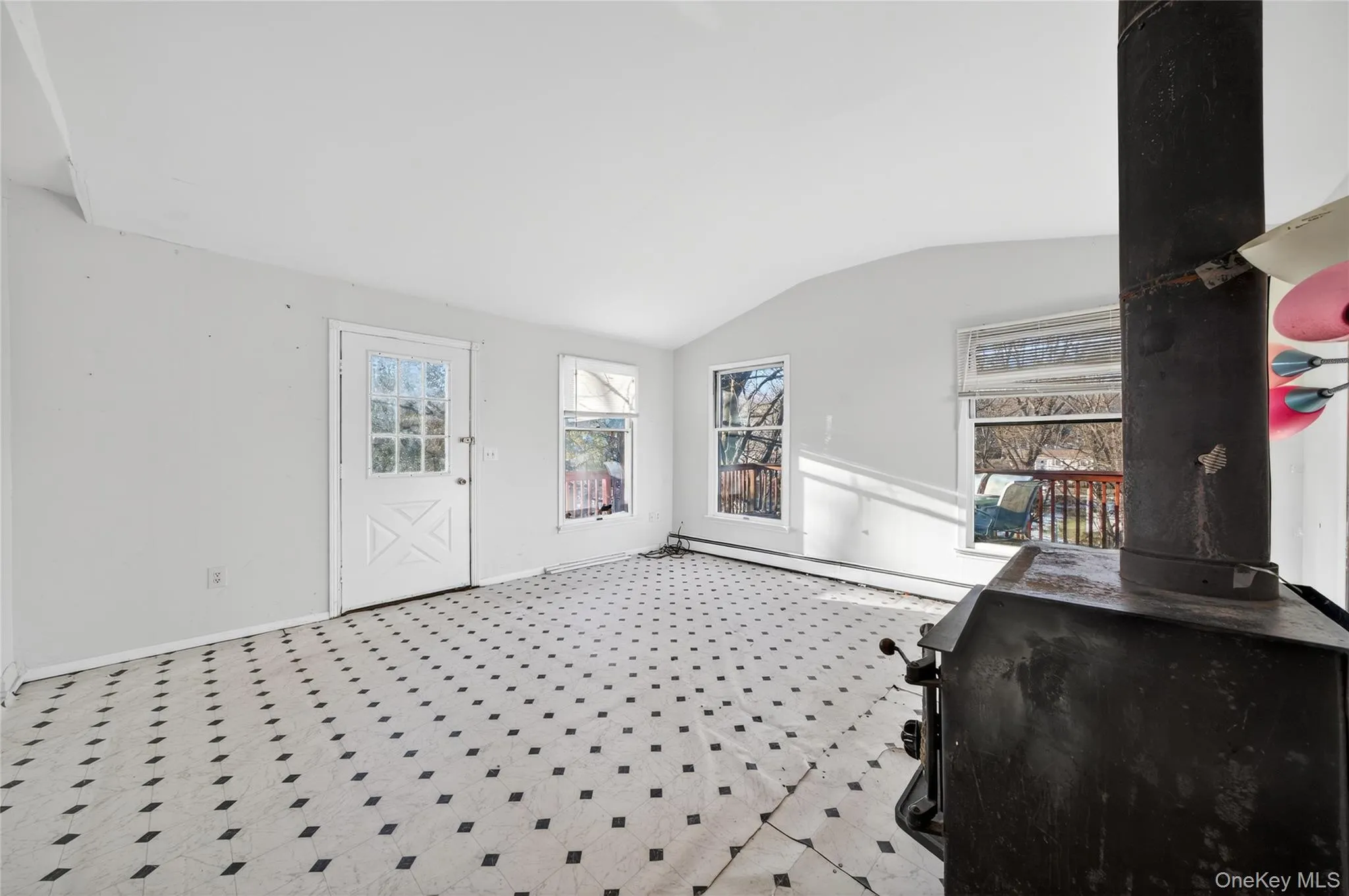 Foyer with lofted ceiling, a baseboard radiator, tile patterned floors, and a wood stove Foyer with lofted ceiling, a baseboard radiator, tile patterned floors, and a wood stove