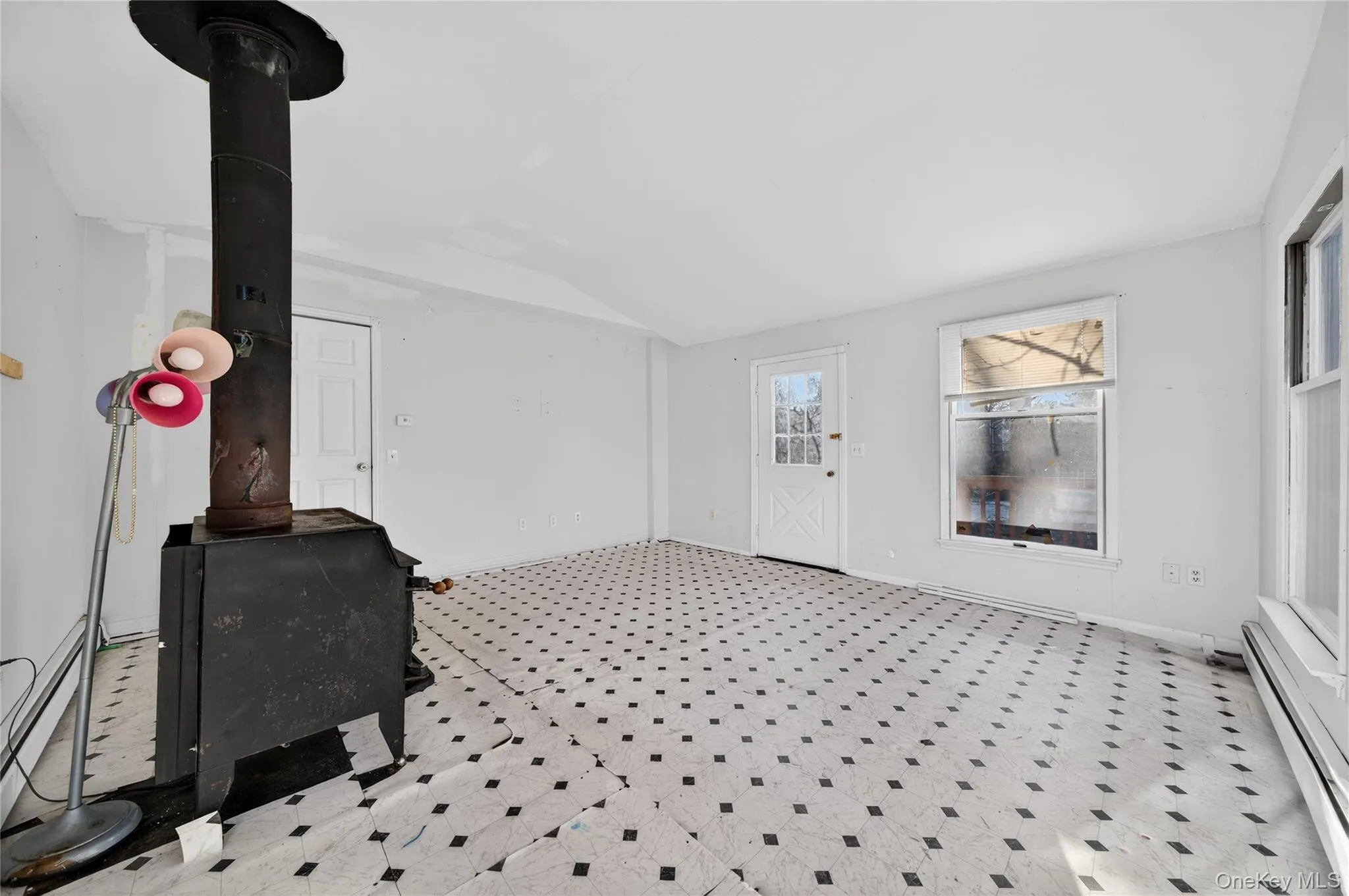 Entryway with a wood stove, baseboard heating, tile patterned floors, and vaulted ceiling Entryway with a wood stove, baseboard heating, tile patterned floors, and vaulted ceiling